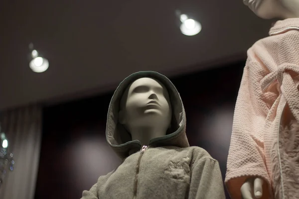Mannequins in robes. Plastic figures of people in home clothes. Showcase of a clothing store. Artificial lighting. Mannequin of woman and child.