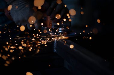 Öğütücüyle öğütülmüş metal. Metal işleme atölyesinde çalışıyorum. Çelik dikişleri temizliyorum. Adam elektrikli bir aletle çalışıyor. Metal ısıtmadan kıvılcımlar.