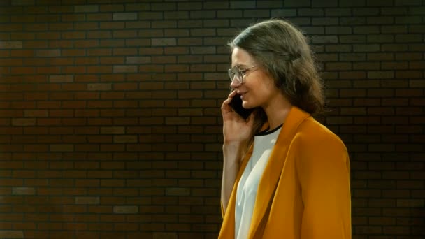 Jonge vrouw in gele jas spreekt telefonisch 05 — Stockvideo