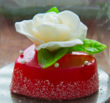 Kırmızı marmelat kalbine yeşil yaprakları ile beyaz gül. Aşıklar ve düğünler için lezzetli tatlılar.