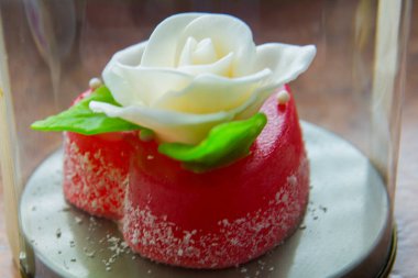 Kırmızı marmelat kalbine yeşil yaprakları ile beyaz gül. Aşıklar ve düğünler için lezzetli tatlılar.