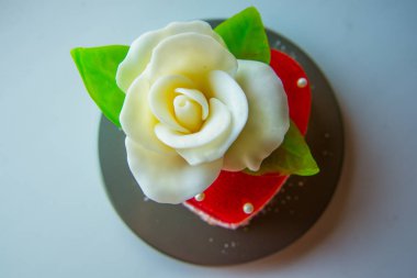 Kırmızı marmelat kalbine yeşil yaprakları ile beyaz gül. Aşıklar ve düğünler için lezzetli tatlılar.