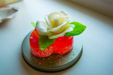 Kırmızı marmelat kalbine yeşil yaprakları ile beyaz gül. Aşıklar ve düğünler için lezzetli tatlılar.