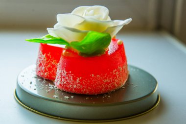 Kırmızı marmelat kalbine yeşil yaprakları ile beyaz gül. Aşıklar ve düğünler için lezzetli tatlılar.