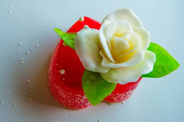 Rose blanche aux feuilles vertes sur un cœur de marmelade rouge, bonbons pour amants et mariages . — Photo