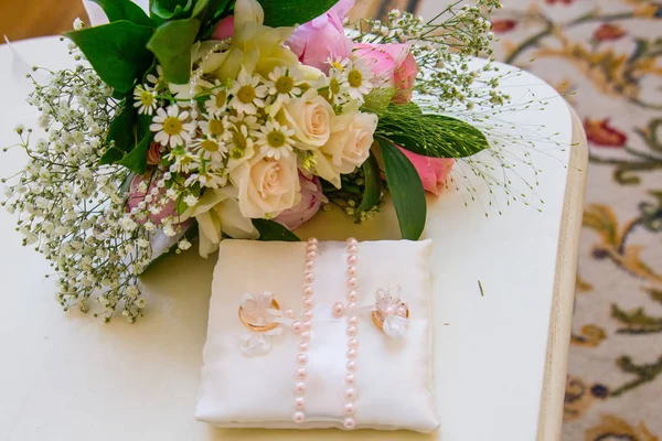 Twee gouden ringen zijn op de bruiloft kussen. Mooie bloemen op uw trouwdag. Boeket rozen van madeliefjes — Stockfoto