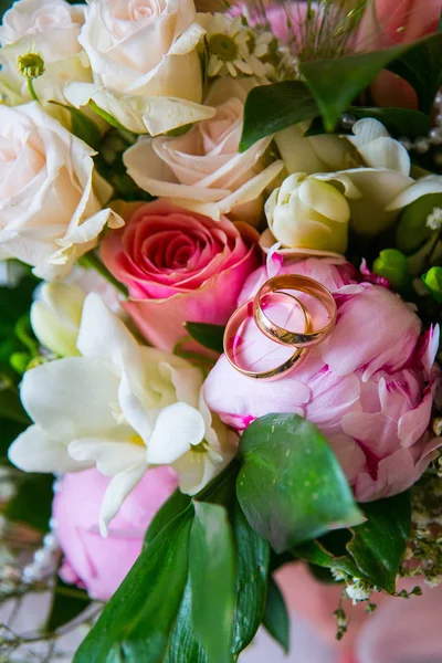 Dos anillos de oro están en el ramo de novias. Hermosas flores en el día de su boda —  Fotos de Stock