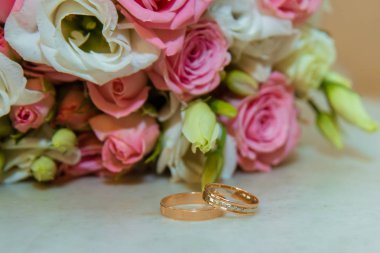 Altın alyans. Pembe güller ve beyaz çiçekler gelinler buket Romantik angajman iki elmas yüzük vardır
