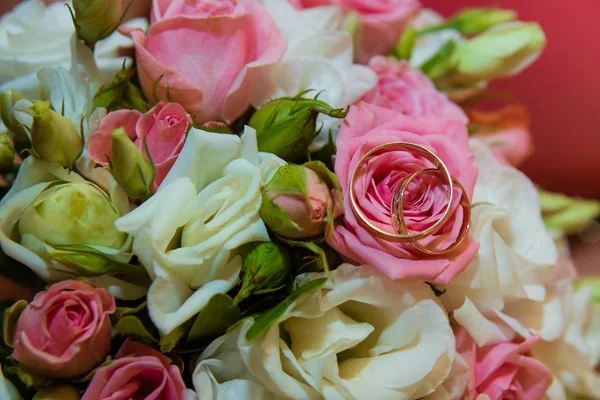 Anillo de oro de boda. Romántico compromiso dos anillos de diamantes están en el ramo de novias de rosas rosadas y flores blancas —  Fotos de Stock