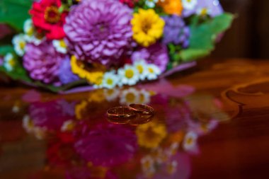 Nikah yüzüğü. Gelin ve damat alışılmadık bir buket çiçek papatya ile ilgili iki altın yüzük.