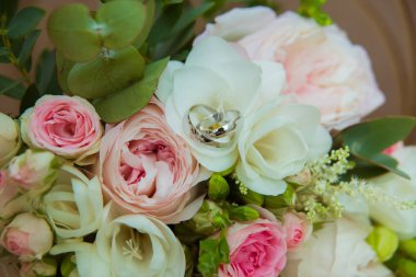 Beyaz altın alyans. Gelin ve damat ve pembe güller ve beyaz çiçek bir buket iki platin yüzük