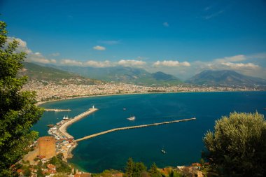 Güzel manzara yukarıdan şehir: mavi deniz, dağlar, deniz feneri, duvarlar ve bağlantı noktası. Alanya, Antalya bölgesinde, Türkiye, Asya