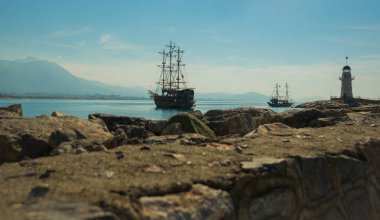 Korsan tarzı gemi ve Alanya sahil kapalı bir deniz feneri. Deniz ve dağlar ufukta. Alanya Yarımadası, Antalya bölgesinde, Türkiye, Asya