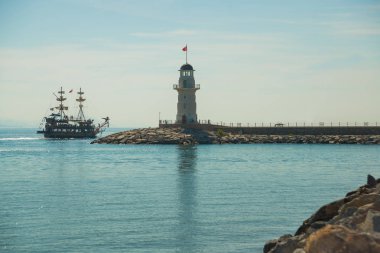 Korsan tarzı gemi ve Alanya sahil kapalı bir deniz feneri. Deniz ve dağlar ufukta. Alanya Yarımadası, Antalya bölgesinde, Türkiye, Asya