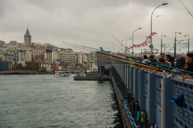 İnsanlar bulutlu bir havada Galata Köprüsü 'nden balık avlıyor. Uzak Galata kulesinde ve evde. İstanbul, dünyada iki kıtada yer alan tek metropol..