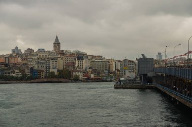 İnsanlar bulutlu bir havada Galata Köprüsü 'nden balık avlıyor. Uzak Galata kulesinde ve evde. İstanbul, dünyada iki kıtada yer alan tek metropol..