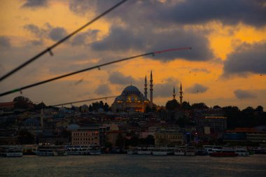 Istanbul, Türkiye: bulutlu, güzel gün batımı uzaktan sen köprü ve Süleymaniye Camii aydınlatma ile görebilirsiniz. Balıkçılık çubuklar.