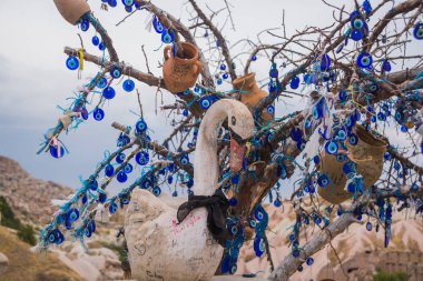 Oyuncak kuğu arzuları tree yakınındaki beyaz. Nazar ağacında arkasında Uçhisar Kalesi, Kapadokya, Türkiye.