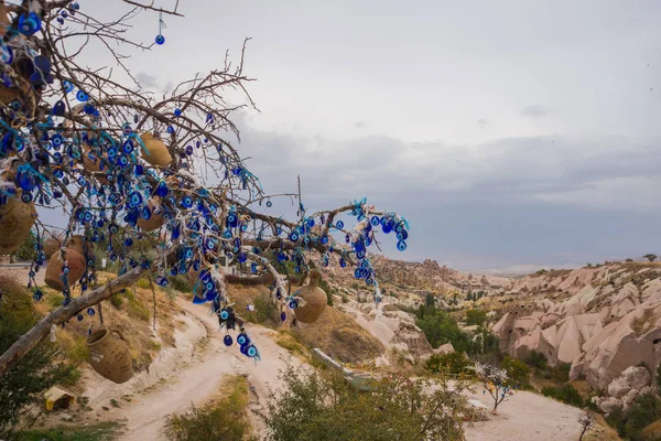 Evil eye in tree behind Uchisar Castle in Cappadocia, Uchisar, Turkey. Tree hanging Nazar amulets, a special eye-shaped objects that protect against the evil eye