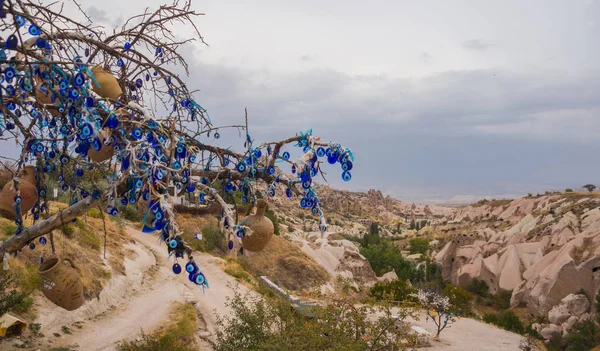 Evil eye in tree behind Uchisar Castle in Cappadocia, Uchisar, Turkey. Tree hanging Nazar amulets, a special eye-shaped objects that protect against the evil eye