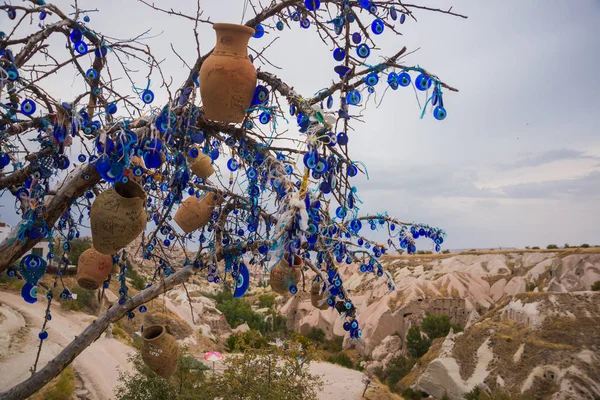 Evil eye in tree behind Uchisar Castle in Cappadocia, Uchisar, Turkey. Tree hanging Nazar amulets, a special eye-shaped objects that protect against the evil eye