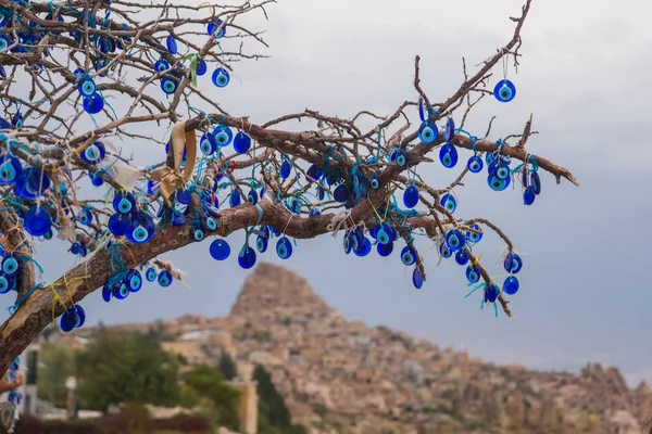 Evil eye in tree behind Uchisar Castle in Cappadocia, Uchisar, Turkey. Tree hanging Nazar amulets, a special eye-shaped objects that protect against the evil eye