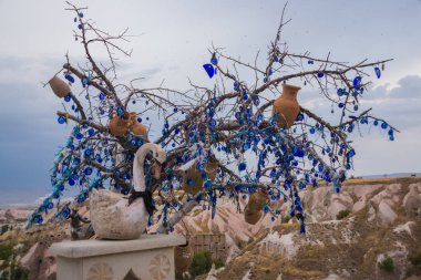Oyuncak kuğu arzuları tree yakınındaki beyaz. Nazar ağacında arkasında Uçhisar Kalesi, Kapadokya, Türkiye.