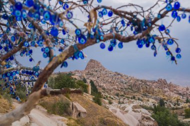 Nazar ağacında Uçhisar Kalesi Kapadokya, Türkiye'de arkasında. Nazar muska, nazar karşı korumak özel bir göz şeklinde nesneleri asılı ağaç