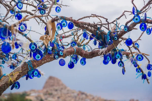 Evil eye in tree behind Uchisar Castle in Cappadocia, Turkey. Tree hanging Nazar amulets, a special eye-shaped objects that protect against the evil eye