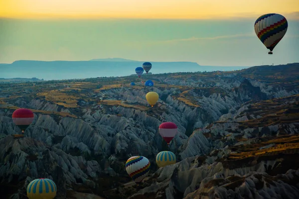 卡帕多西亚 土耳其 卡帕多西亚在日出时 景观热气球在阳光和薄雾飞越山谷 气球对蓝天在飞行 五颜六色的有趣的娱乐形式的运输 飞行在气球的空气中 — 图库照片