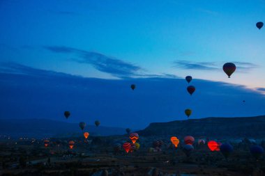 Kapadokya, Göreme, Anadolu, Türkiye. Dağların üzerinden uçan sıcak hava balonları günbatımı Kapadokya, vintage doğa arka plan manzara. Turistler için en sevdiğiniz eğlencelerin.