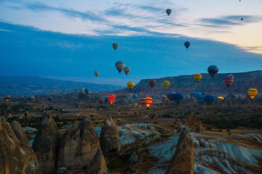 Kapadokya, Göreme, Anadolu, Türkiye. Gün batımı sıcak hava balonları bir dağ Kapadokya Göreme Milli Parkı Türkiye'nin turistik, vintage doğa arka plan iniş. Turistler için en sevdiğiniz eğlencelerin.
