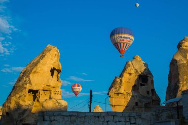 Göreme, Kapadokya Anadolu, Turkey: Eski taş evleri ve balon Göreme güneşli havalarda mavi gökyüzünde karşı. Sıcak hava balonu turistler için popüler bir uçuş olduğunu