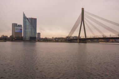 Riga, Letonya: Gökdelenler arkasında dur. Güzel sonbahar manzara. Nehir ve bulutlu havalarda köprü görünümü.