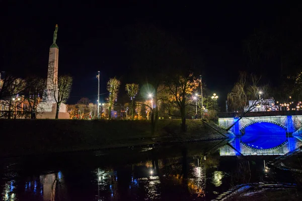 Riga, Letonya: Letonya 100 yıl. Özgürlük Anıtı, şeref kıtası askerler. Sonbaharda Letonyalı Anavatan ve özgürlük için anıt kitabe. Gece manzarası. Güzel bir gece manzara mavi bir ışık Köprüsü ile. Bastejka yuvarlak tezgah