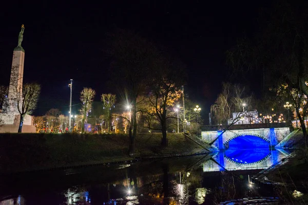 Riga, Letonya: Letonya 100 yıl. Özgürlük Anıtı, şeref kıtası askerler. Sonbaharda Letonyalı Anavatan ve özgürlük için anıt kitabe. Gece manzarası. Güzel bir gece manzara mavi bir ışık Köprüsü ile. Bastejka yuvarlak tezgah
