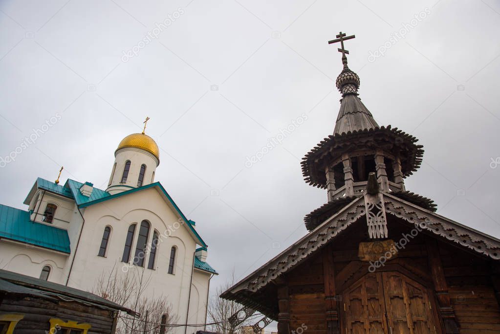 SAINT-PETERSBURG, RUSSIA: Wooden chapel with a bell tower and carved porch at the church of the Holy St. Seraphim Vyritsky. Beautiful temple with a Golden dome against the sky.