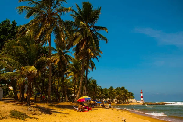 SALVADOR, BAHIA, BRASILE: Farol De Itapua sul mare mosso. Paesaggio tropicale sulla spiaggia con palme e faro — Foto Stock