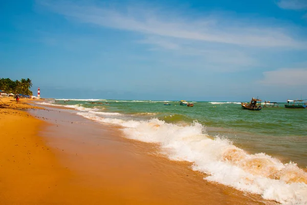 SALVADOR, BAHIA, BRASIL: Farol De Itapua en el mar agitado. Faro en la playa en tiempo soleado . — Foto de Stock
