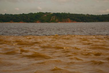 Manaus, Amazonas, Brazil: The merger of the two colored river, Rio Negro, Solimoes. Meeting, multi-colored waters do not mix, and continue the way side by side, thus each river remains with the own co clipart