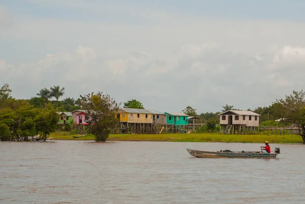 Amazonská řeka, Amazonas, Brazílie: rybář tančí na lodi. Dřevěné místní chaty, domy na řece Amazonky v Brazílii. — Stock fotografie
