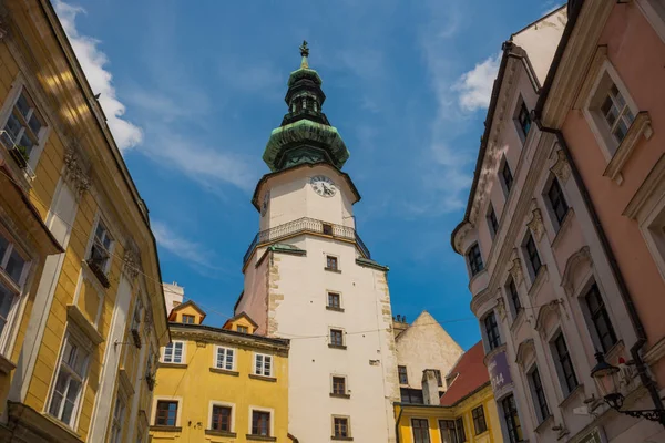 Bratislava, Slovensko: městská ulice denní pohled na historické budovy a slavná věž svatého Michala na pozadí s modrou oblohou — Stock fotografie