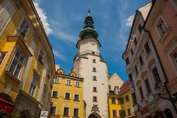 Bratislava, Slovensko: městská ulice denní pohled na historické budovy a slavná věž svatého Michala na pozadí s modrou oblohou — Stock fotografie