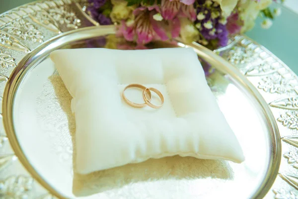 Los anillos de boda están en una almohada blanca y tristemente el ramo de la novia . — Foto de Stock