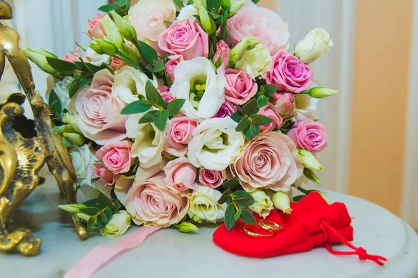Прекрасный нежный свадебный букет из белых и розовых роз и обручальных колец жениха и невесты . — стоковое фото