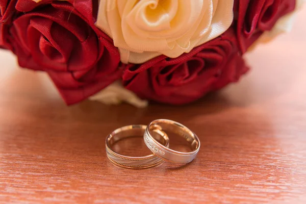 Anéis de casamento da noiva e do noivo em um lindo buquê de casamento de rosas vermelhas e brancas — Fotografia de Stock