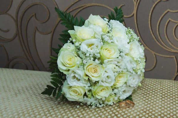 Piękny delikatny bukiet ślubny z białych róż i obrączki panny młodej i pana młodego. — Zdjęcie stockowe