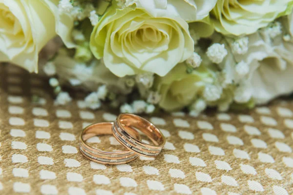 Beautiful delicate wedding bouquet of white roses and wedding rings of the bride and groom. — Stock Photo, Image