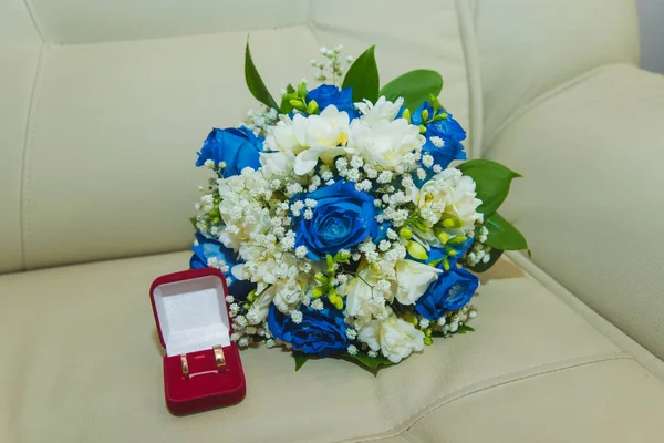 Piękny delikatny bukiet ślubny z niebieskich róż i obrączki panny młodej i pana młodego w czerwonym pudełku — Zdjęcie stockowe
