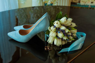 Beyaz lale güzel bir düğün buketi üzerinde gelin ve damat alyans. Mavi düğün ayakkabıları